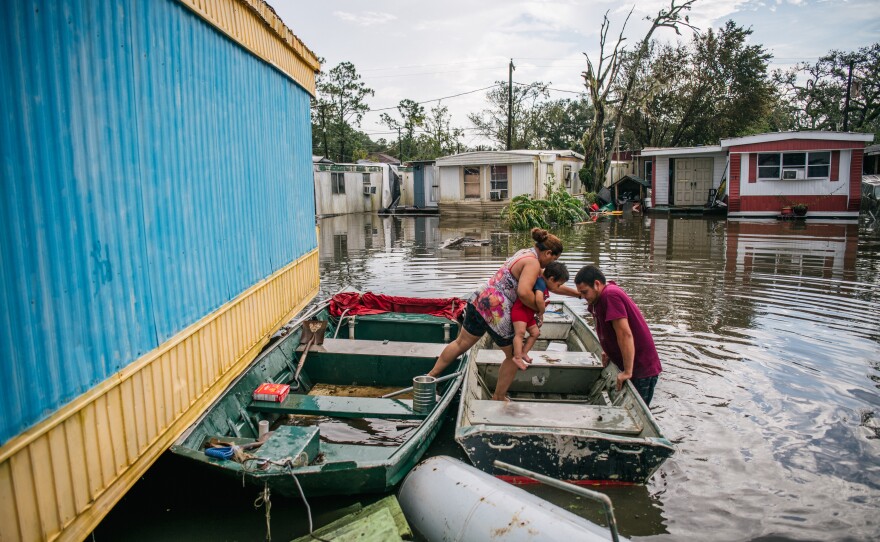 Marlon Maldonado helps his wife and child into a boat on Aug. 31 in Barataria, La., to travel to their home after it flooded during Hurricane Ida.