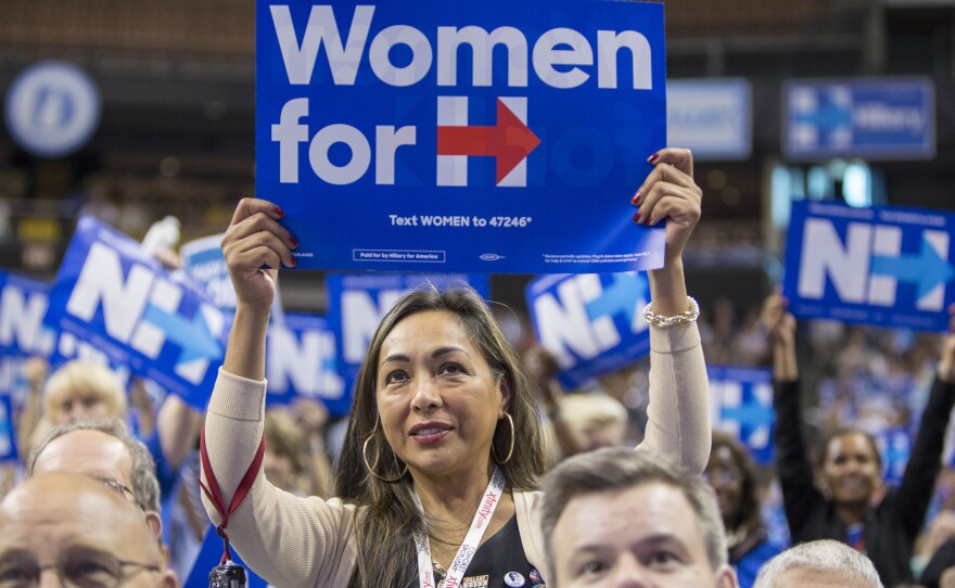 A supporter holds up a "Women for H" sign while Hillary Clinton speaks at the New Hampshire Democratic Party Convention last weekend in Manchester. When Clinton ran eight years ago, she downplayed the potential historical significance of her candidacy. But this time around, she has made so-called women's issues centerpieces of her campaign.