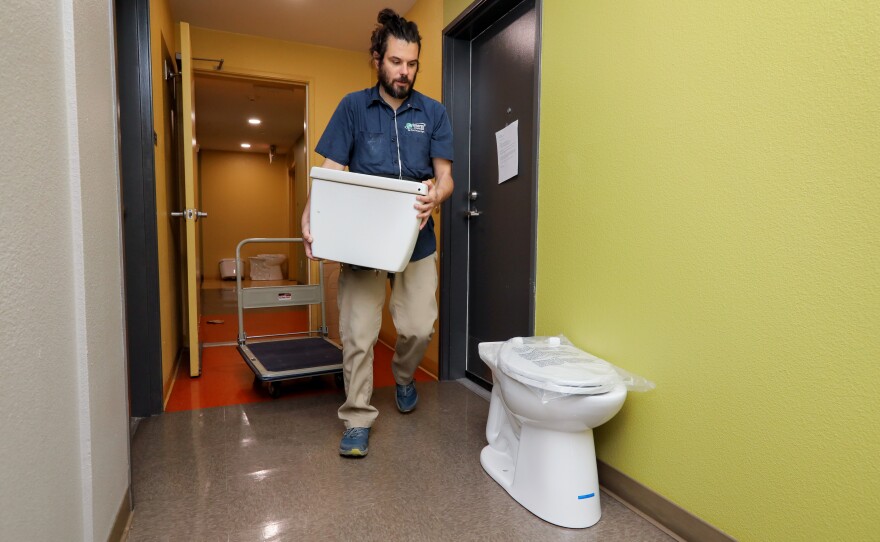 A worker prepares a low-flow toilet for install.
