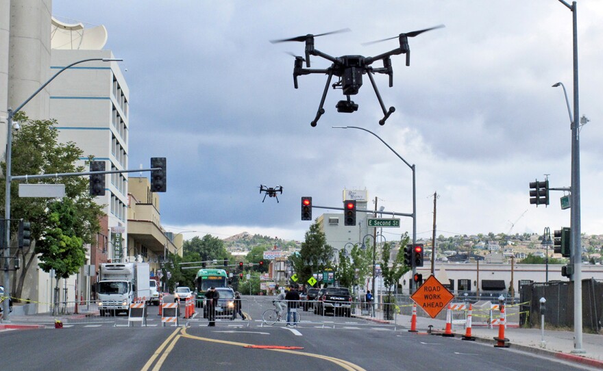 In this May 21, 2019 photo, two drones fly above Lake Street in downtown Reno, Nev., on, as part of a NASA simulation to test emerging technology that someday will be used to manage travel of hundreds of thousands of commercial, unmanned aerial vehicles (UAVs) delivering packages. It marked the first time such tests have been conducted in an urban setting.