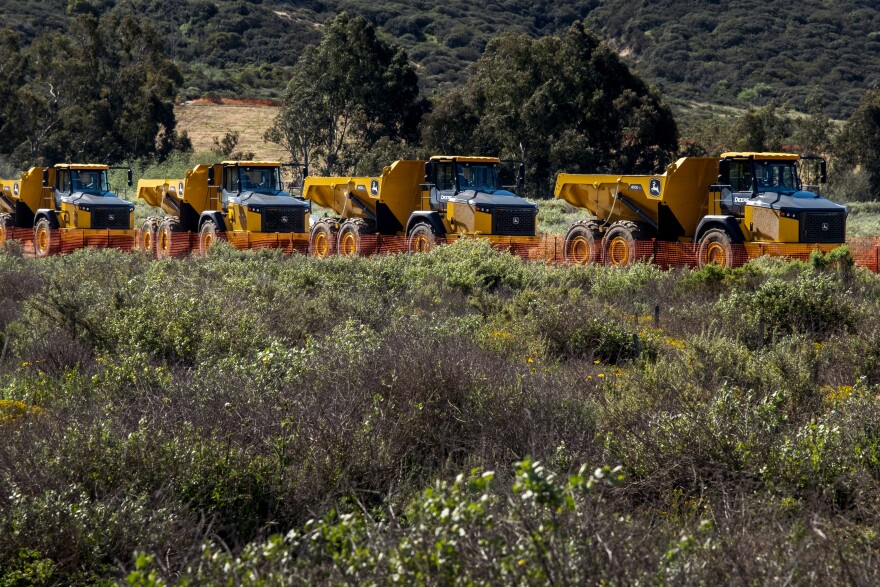 Dump trucks wait near the San Dieguito River by to move about 84 acres worth of dirt to help restore the land to its natural state, Del Mar, March 23, 2022.