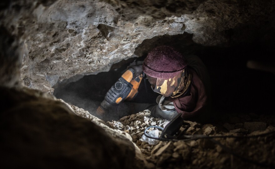 A zama-zama uses a jackhammer to break up rock in an abandoned De Beers mine.