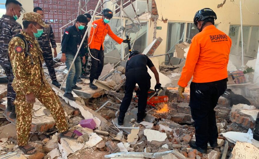 In this photo released by the Indonesian National Search and Rescue Agency (BASARNAS), rescuers attempt to clear debris at building damaged by an earthquake in Maumere, East Nusa Tenggara Province, Indonesia, Saturday, Aug. 15, 2026.