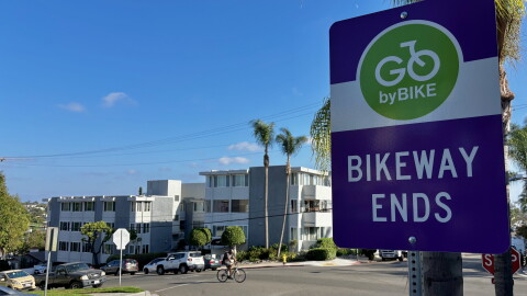 A sign reads "Go by bike — bikeway ends" as a cyclist rides past on Robinson Avenue, Sept. 17, 2026.
