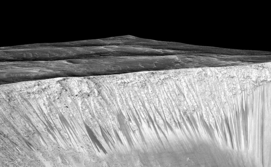 Streaks a few hundred feet in length appear on the walls of Garni crater on Mars. Scientists suspect they are formed by the flow of briny, liquid water.