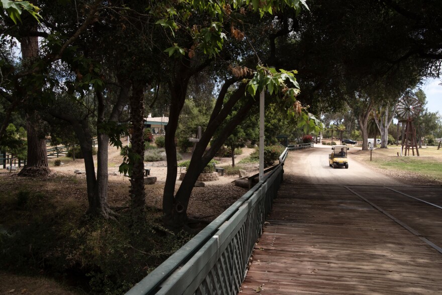 A worker drives through the shade of the oaks along the creek on the campus of Green Oaks Ranch on June 10, 2024, in Vista, CA