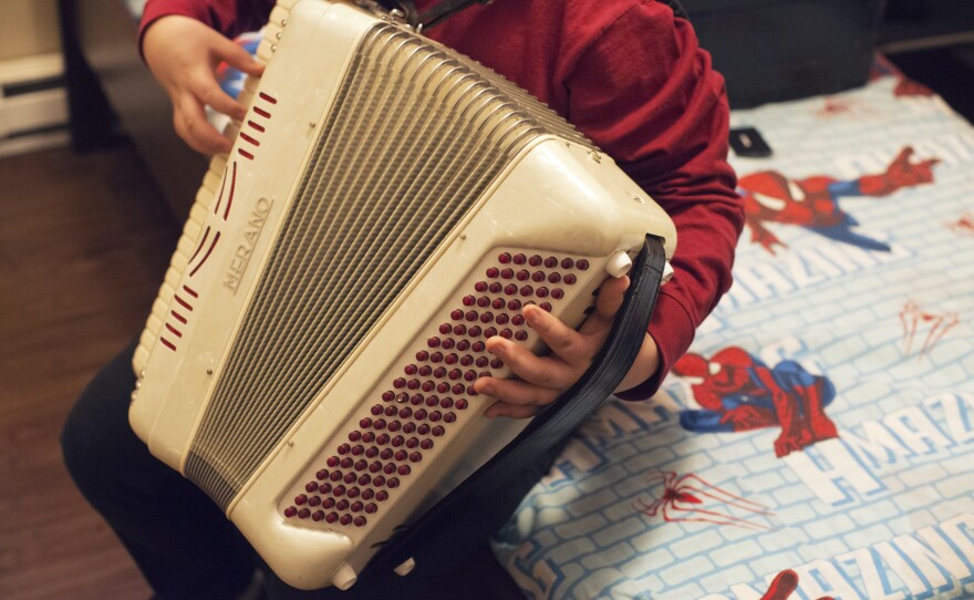 Alex, 14, plays the accordion in his bedroom. He has been learning how to play one of his dad's favorite songs, <em>La Puerta Negra</em>, or "The Black Door." His grades suffered during his father's detention.