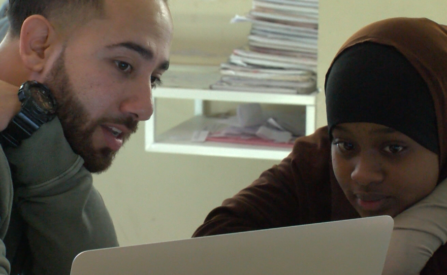 Elijah Gonzalez helps a student with her essay, Dec. 5, 2016.