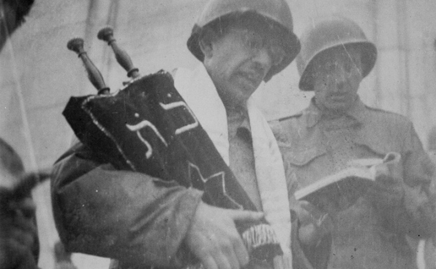 Rabbi Chaplain David Max Eichhorn holding a torah saved in France and performing a Jewish service in the Zeppelin Stadium in Nuremburg, Germany. April, 1945.