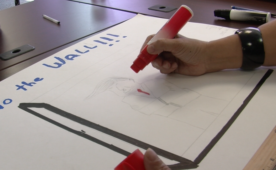Martina Pappas sketches Donald Trump in a straitjacket, with a border fence around his body at the San Diego County Democratic Party office, May 26, 2016.