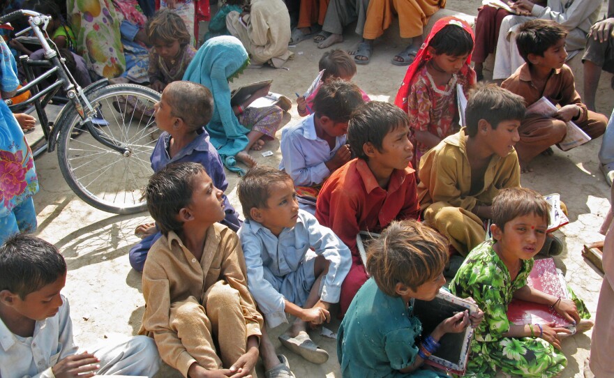 So many children gather at the cowshed for instruction that they spill outside.