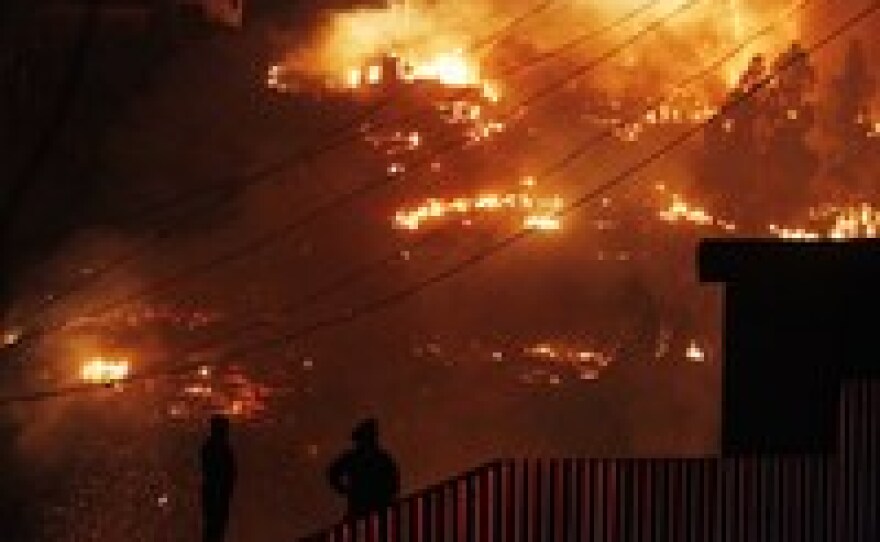 Emergency responders watch as an out-of-control forest fire destroys homes in Valparaiso, Chile, Sunday. The fire is blamed for destroying thousands of homes.