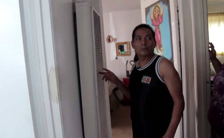 Abraham Rojas points to a non-functioning wall heater in his apartment in December 2014. Rojas and his wife sought help for this and other problems from a tenants rights attorney, in part because a language barrier kept them from getting adequate service from city inspectors.