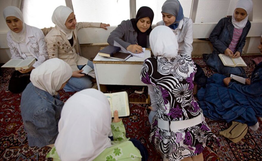 A teacher instructs her student on correct pronunciation of Qur'anic verse.