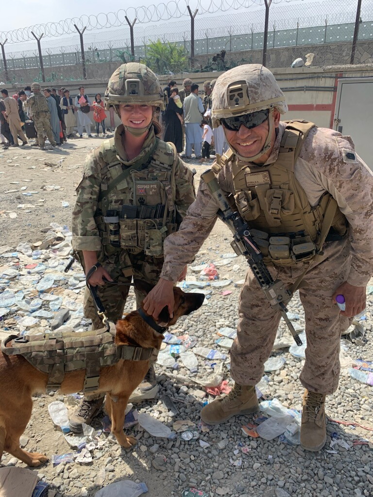 Sgt. Maj. Hector Rivera pets a service dog held by a British soldier outside Hamid Karzai International Airport during the mission to evacuate Afghans from Kabul in August, 2021.