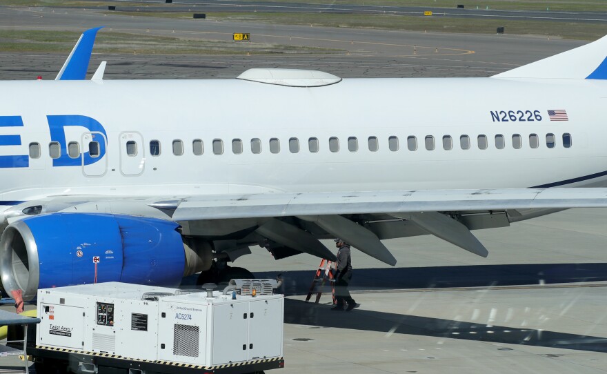 A Medford Jet Center worker walks under a United Boeing 737-824 that landed at Rogue Valley International-Medford Airport from San Francisco with a missing panel on Friday in Medford, Ore.