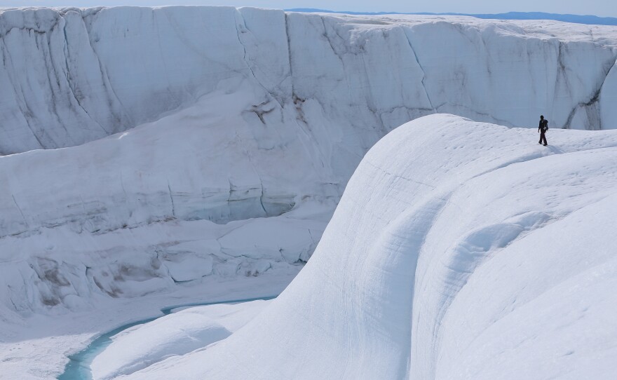 A researcher looks at a canyon created by a meltwater stream on the glacial ice sheet in Greenland in 2013.