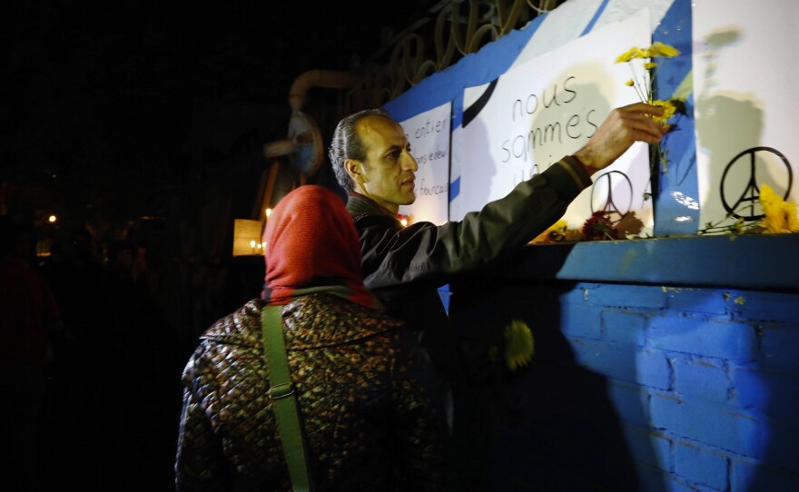 In Tehran, Iranians place flowers and light candles in front of France's embassy.