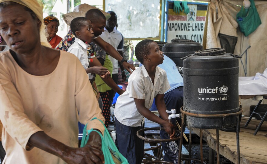 The WHO says the current Ebola outbreak is an emergency in the Democratic Republic of the Congo and the region — but not on the international level. Here, people arriving from the DRC on Friday wash their hands with chlorinated water to prevent the spread of infection at the Mpondwe border crossing in western Uganda.