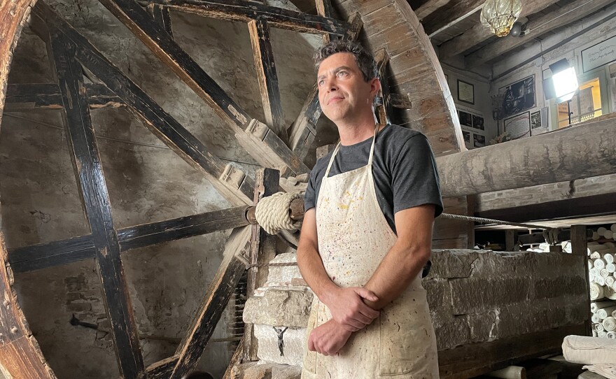 Gabriele stands next to the 17th century Mangano, a giant wheel that presses and stretches the fabric at Marchi, a textile printing house founded in 1633 in Bologna, Italy.