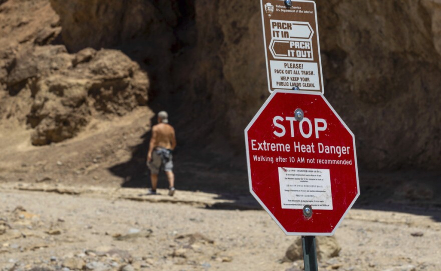 A hiker passes a sign warning of extreme heat at the start of the Golden Canyon trail, in Death Valley National Park, Calif., July 11, 2023. Parts of California, Nevada and Arizona are expected to bake this week as the first heat wave of the season arrives with triple-digit temperatures forecast for areas including Phoenix, which last summer saw a record 31 straight days of at least 110 degrees Fahrenheit.