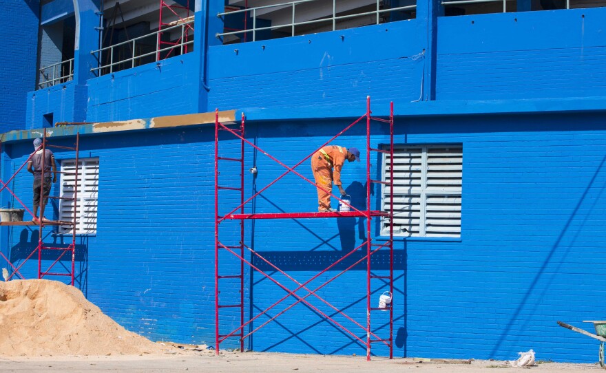 Workers paint the walls outside the Estadio Latinoamericano in Havana, on Tuesday.