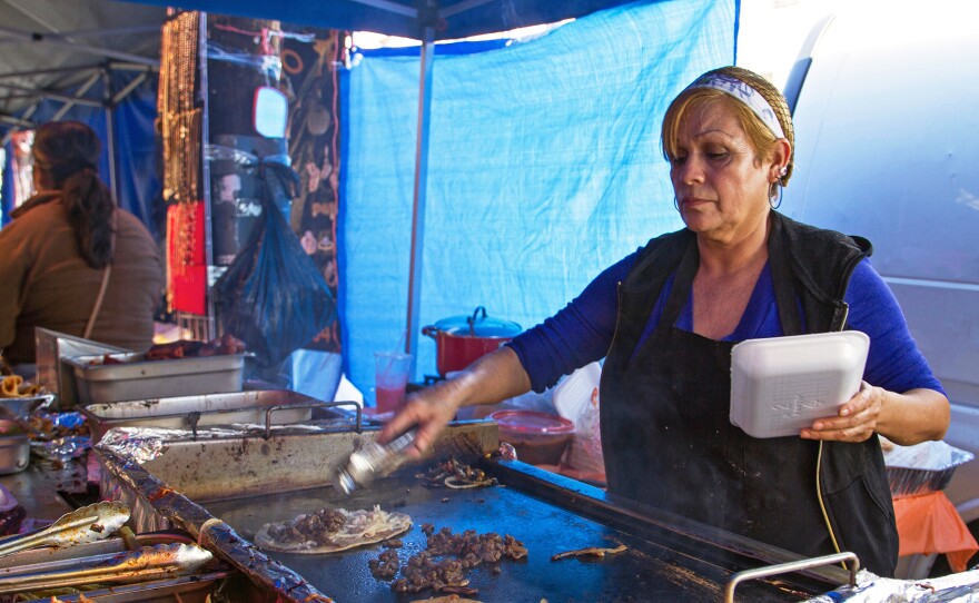 A street vendor makes huaraches and quesadillas on the sidewalk in the piñata district in Los Angeles. LA is the only major U.S. city where selling food on the sidewalk is illegal. President Trump's immigration policies have pushed the city council to change the law. But the devil is in the details.