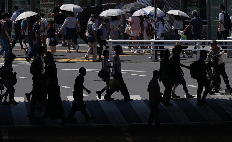 People walk across a pedestrian crossing under the scorching sun on Tuesday, Aug. 25, 2026, in Tokyo.