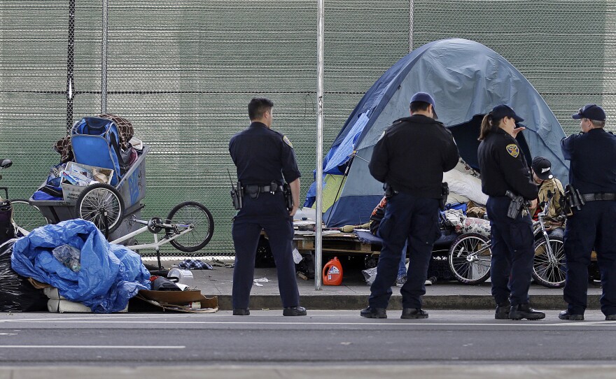 San Francisco police officers wait while homeless people collect their belongings. Nearly a quarter of the country's homeless population lives in California.