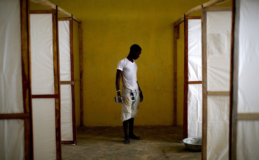 A worker stands near dividers intended to separate patients in an Ebola treatment facility under construction in the Port Loko district of Sierra Leone in 2014.