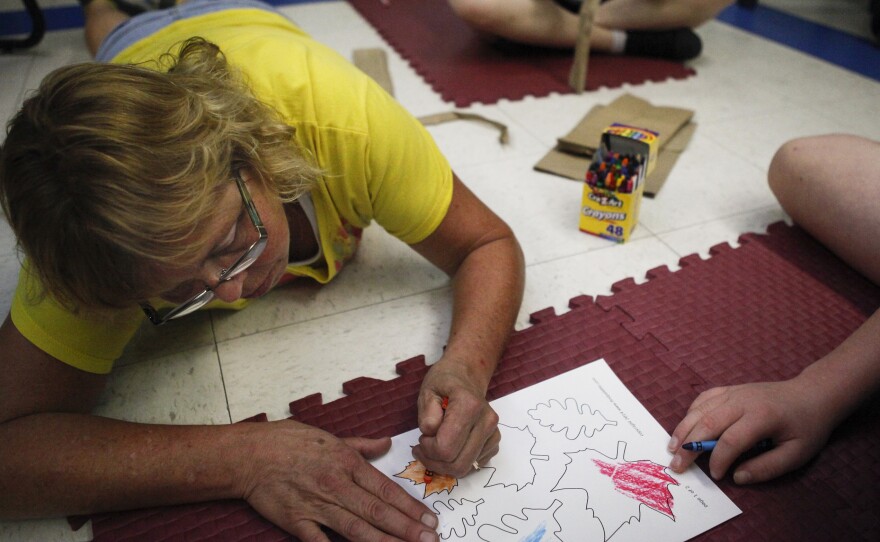 Elder colors paper leaves for the Life Skills tree. When they finish coloring, students will write skills they want to master on the leaves.