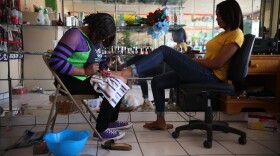 In this May 5, 2018 photo, 30-year-old Haitian migrant Marie Toussaint gives a pedicure to a customer at her local beauty salon in downtown Tijuana, Mexico. Toussaint is one of the most successful Haitian migrants in Tijuana. She opened her beauty salon with money she loaned from an uncle in Los Angeles.