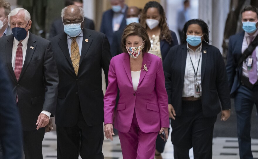 Speaker of the House Nancy Pelosi, D-Calif., (center) joined from left by House Majority Leader Steny Hoyer, D-Md.; and House Majority Whip James Clyburn, D-S.C., walks to update reporters after day of delays in the vote to advance President Joe Biden's domestic policy package at the U.S. Capitol on Friday.