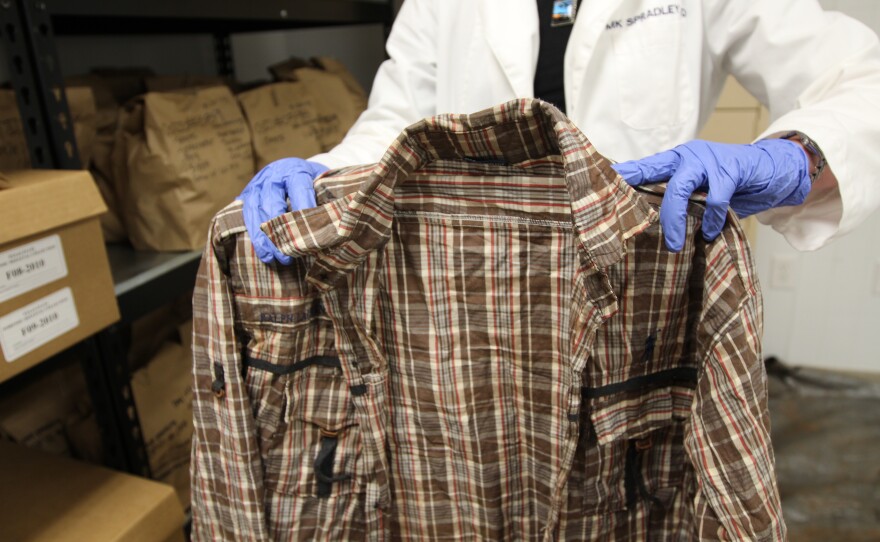 Forensic anthropologist Kate Spradley holds the shirt of a deceased Salvadoran migrant. The shirt's discovery set off a chain of events that ended with the successful but rare DNA confirmation of a migrant who perished in Texas after crossing the U.S.- Mexico border. 