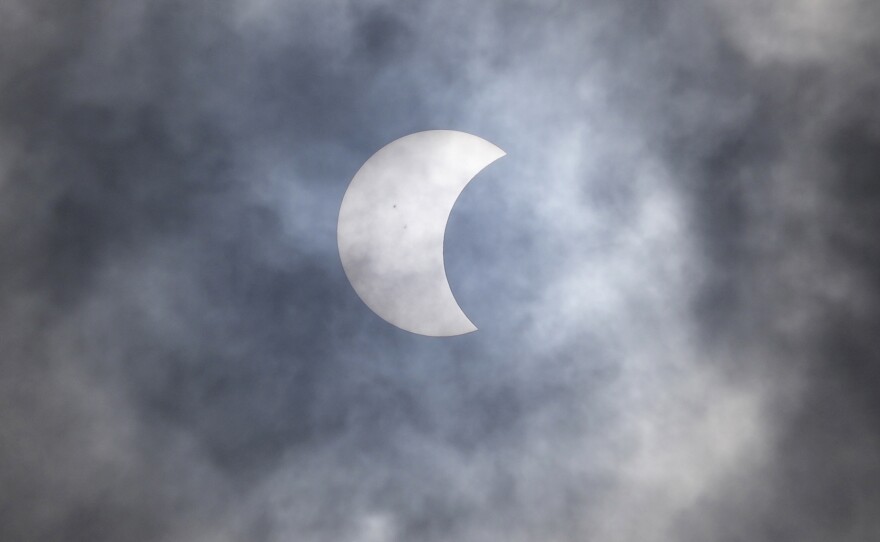 A partial solar eclipse is seen through the cloud over Jakarta, Indonesia, Thursday, April 20, 2023.