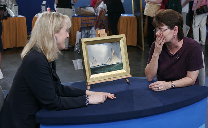 Nan Chisholm (left) appraises a J. E. Buttersworth oil painting, ca. 1885 in Tampa, Fla.
