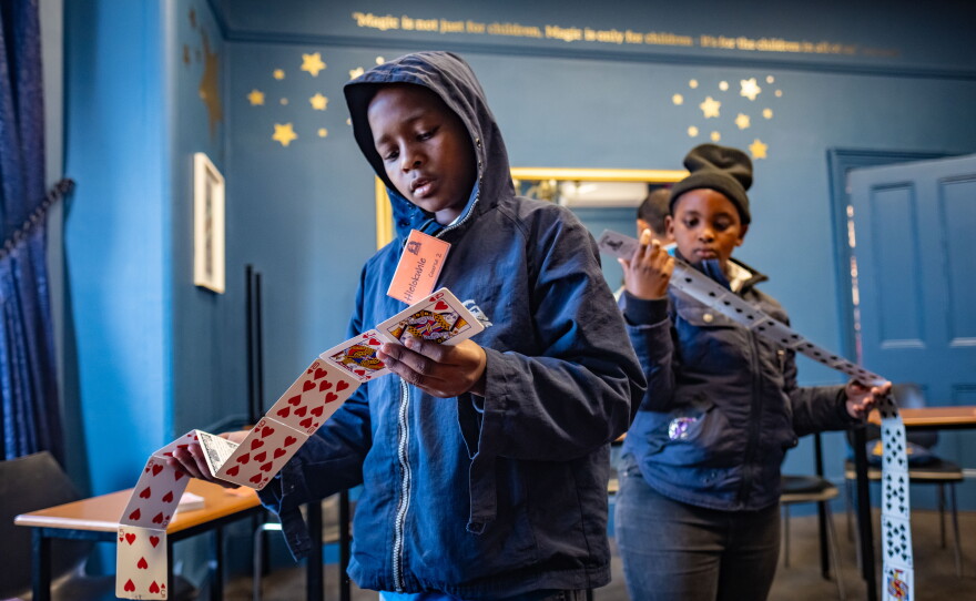 Students examine a set of trick playing cards during a class at the College of Magic, whose pupils are ages 10 to 18.