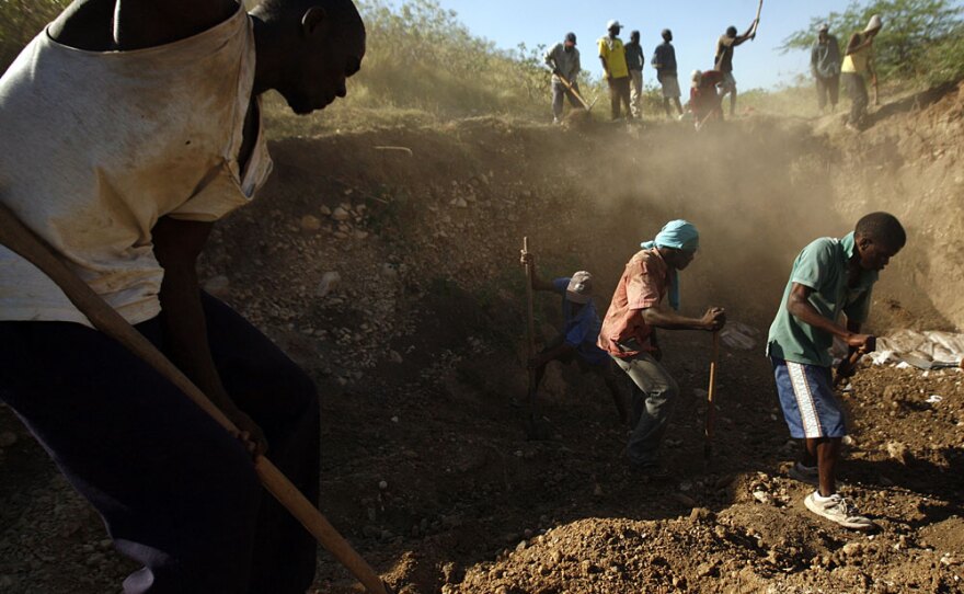 Workers bury unidentified victims of the earthquake in a mass grave outside Port-au-Prince, Haiti, last month.