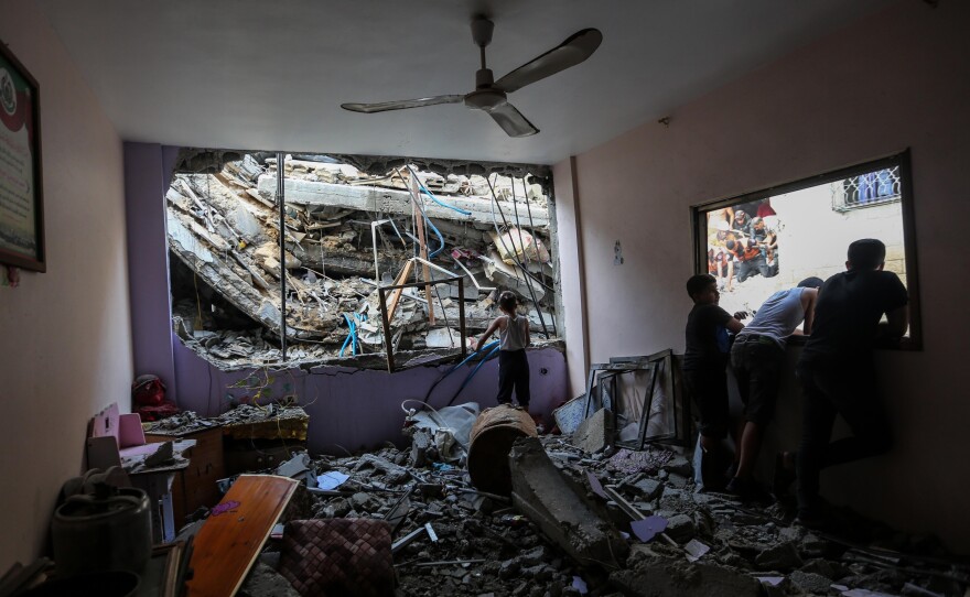 People look out through damaged windows at buildings destroyed during Israeli air raids in the southern Gaza Strip in Khan Yunis, Gaza. Entering the third week of the conflict, the Israeli army has expanded its military assault.