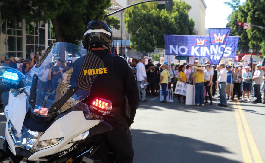 A San Diego police officer watches a crowd of "No Kings" protesters in downtown San Diego on Oct. 18, 2025.