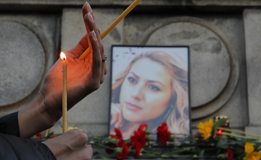 A woman holds a candle next to a portrait of slain journalist Viktoria Marinova during a vigil at the Monument of Liberty in Ruse, Bulgaria, on Monday.