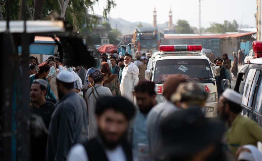 Taliban members and people waiting in Afghanistan can be seen from the Pakistani side of the border crossing at Torkham.