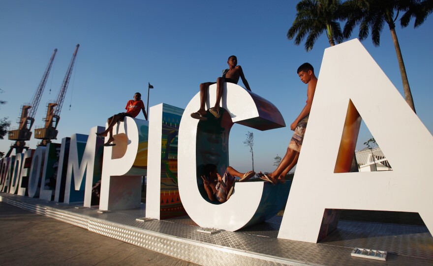 Teenagers sit on a new sign reading "Cidade Olimpica" (Olympic City) in Rio de Janeiro's port district last October. Ahead of this summer's Olympic Games, the port district is undergoing an urban renewal program. Ticket sales have been slow, and many Brazilians cite the poor state of the economy, which is in recession.