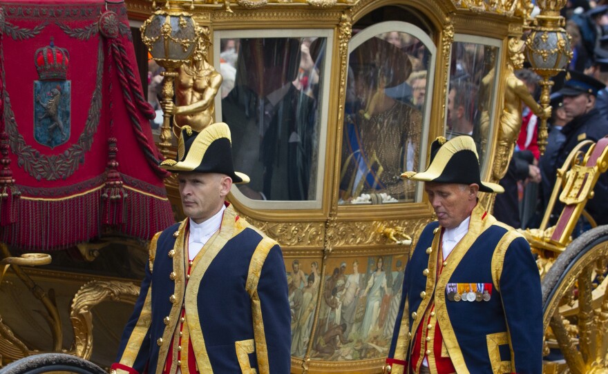 Footmen walk alongside the Golden Carriage as Netherlands' King Willem-Alexander and Queen Maxima arrive at Noordeinde Palace on Sept. 17, 2013.