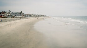 Beachgoers walk along the sand next to the IB Pier in Imperial Beach on September 3, 2024.
