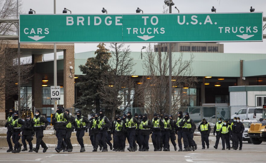 Police arrive to clear protesters and their vehicles from a blockade at the entrance to the Ambassador Bridge in Windsor, Ontario on Saturday.