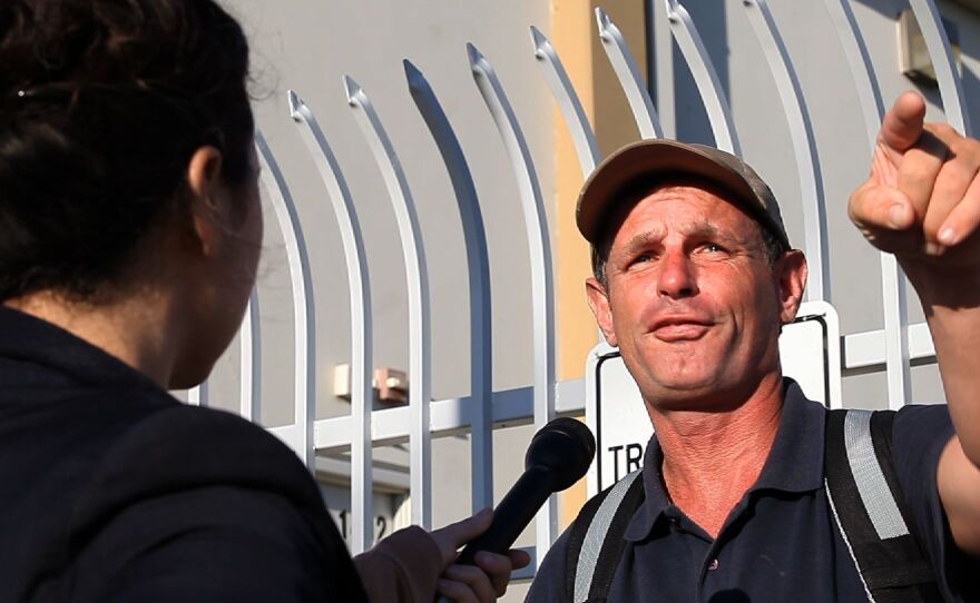 Matt McCarthy, speaking to KPBS metro reporter Sandhya Dirks, points to the benches where he sleeps at night