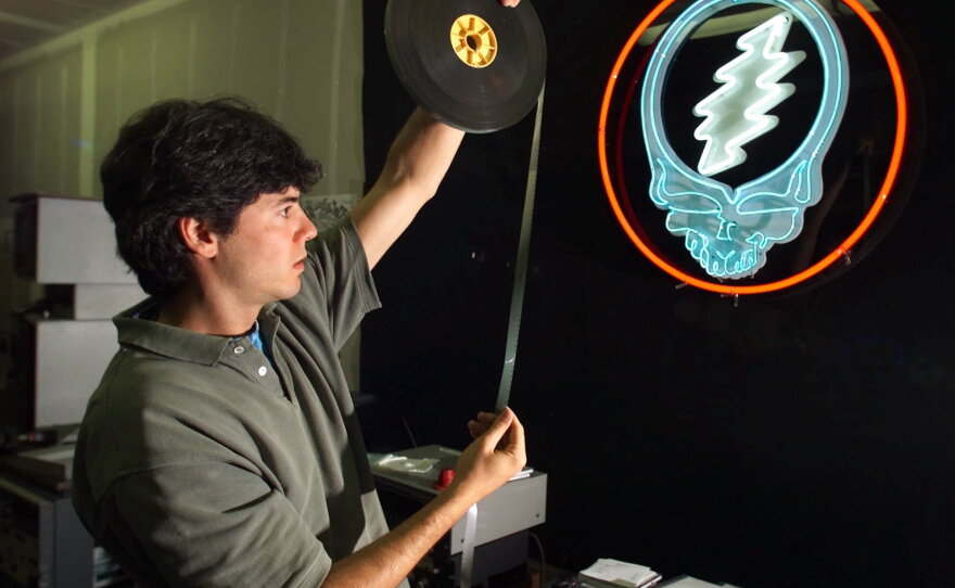 David Lemieux, audiovisual archivist for the Grateful Dead, holds up a piece of 16 mm motion picture film while working at the band's warehouse in Novato, Calif., on Aug. 7, 2000. Despite the band's breakup after leader Jerry Garcia's death in 1995, Grateful Dead Productions runs a multimillion-dollar business from the warehouse in paraphernalia and other merchandise. The Dead's most recognizable emblem, the "Steal Your Face" icon, is on the wall.