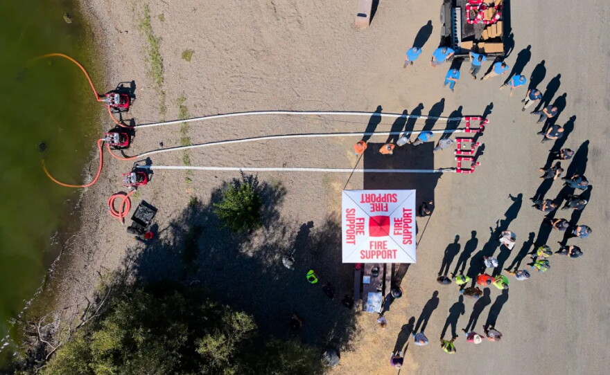 Firefighters and other workers learn how to use remote hydrants on the shore of Clear Lake in Clearlake Oaks on Aug. 27, 2026.