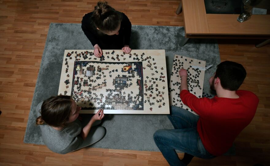 Flat-mates work on a puzzle in their living room in Dortmund, Germany, on March 27, 2020.